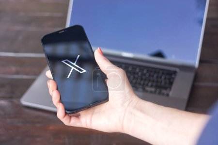 Photo for WROCLAW, POLAND - SEPTEMBER 14, 2023:X logo (formerly Twitter), a social network owned by Elon Musk, displayed on an iPhone screen with a MacBook Pro in the background - Royalty Free Image