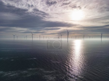 Photo for Birds eye view of the wind turbine producing green energy. Fryslan wind farm drone view - windmill farm in the Netherlands during the sunrise producing renewable energy. - Royalty Free Image