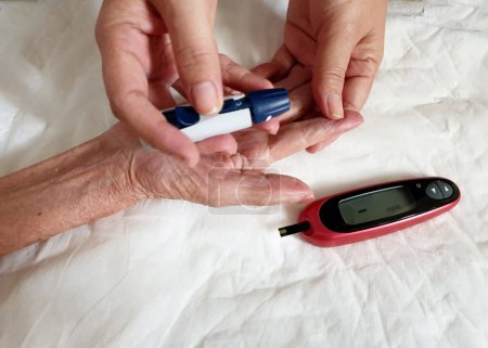 Photo for One of step of checking blood sugar, use the lancing device to puncture of your fingertip with the lancet provided with your test kit, A normal blood glucose level is less than 100 mg dL - Royalty Free Image