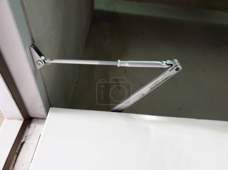 Photo for Door closer: A manual door closer stores the energy used in the opening of the door in a compression or torsion spring and releases it to close the door - Royalty Free Image