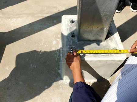 Photo for Project engineer rechecking distance of base plate connection bolts for steel structure of solar carport. - Royalty Free Image