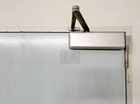 Photo for Door closer: A manual door closer stores the energy used in the opening of the door in a compression or torsion spring and releases it to close the door. - Royalty Free Image