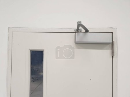 Photo for Door closer : A manual door closer stores the energy used in the opening of the door in a compression or torsion spring and releases it to close the door. - Royalty Free Image