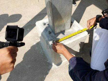 Photo for Project engineer rechecking distance of base plate connection bolts for steel structure of solar carport. - Royalty Free Image