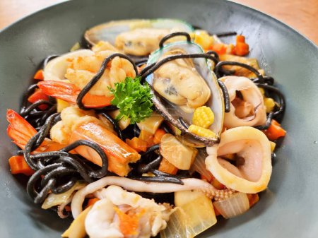 Photo for Close-up the spaghetti black squid with seafood, such as prawn, calamari, mussel, and vegetables. - Royalty Free Image
