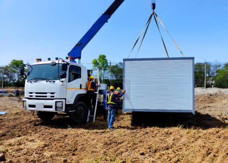 Téléchargez les photos : Les camions-grues transportent les bâtiments de bureaux mobiles ou le bureau du site de conteneurs pour une installation dans la zone du chantier de construction, mobilisation du projet. - en image libre de droit