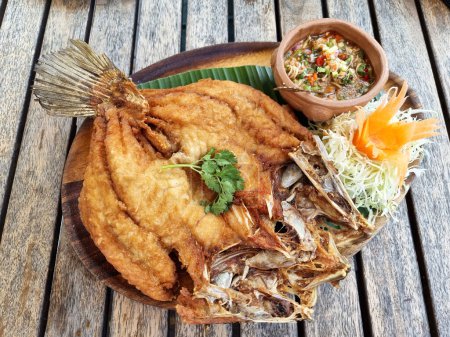 Photo for Deep Fried Sea Bass with Fish Sauce on a wooden table - Royalty Free Image