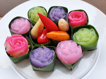 Photo for Traditional colorful sweet Thai desserts on a white plate, such as Deletable Imitation Fruits (Khanom Look Choup) and Khanom Alua Kularb or Rose shaped sweetmeats - Royalty Free Image