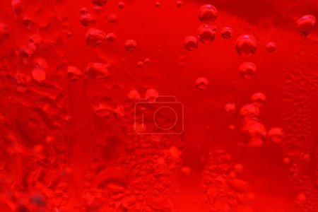 Abstract macro photography of red soda water with bubbles in a drinking glass.