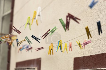 Téléchargez les photos : Pinces à linge multicolores sur une corde sur le fond d'une maison de ville. - en image libre de droit