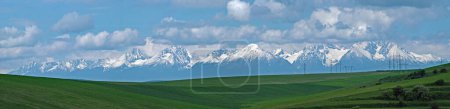 Photo for Panorama of the snow-covered, partially sunlit High Tatras in Slovakia, with a lot of clouds over the tops of the peaks. View from Poprad, Slovakia. - Royalty Free Image