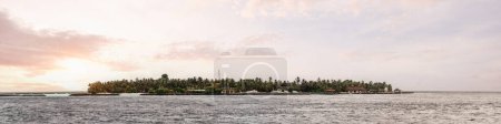 Téléchargez les photos : A panoramic view of a stunning dramatic in shades of purple sunset over the pacific sea, in the Maldives islands; tropical warm sunlight around clouds, the water level at the bottom - en image libre de droit