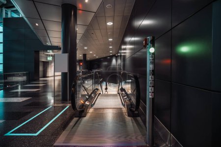 Foto de A capture of a contemporary airport, in Zurich, the area with a selective focus is on moving walkways leading to a lower floor with a green light in front signaling that the passage is allowed - Imagen libre de derechos