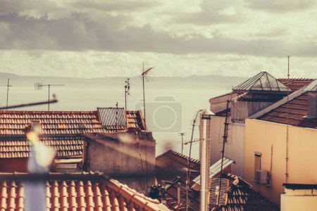 Foto de Cityscape of Lisbon's old town and Tejo's river in the background; Multiple traditional residential homes with orange clay roofs tiles on the hill of Lisbon, Portugal on a warm sunny day with clouds - Imagen libre de derechos