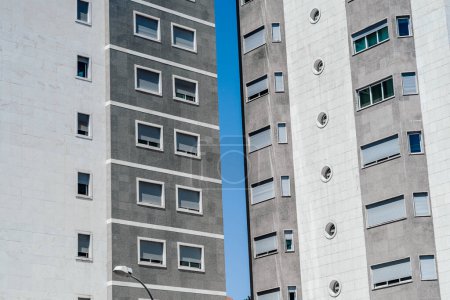 Foto de View of two textured grey color building edifice facades the space between them showcases a long stripe that happens to be the blue sky - Imagen libre de derechos