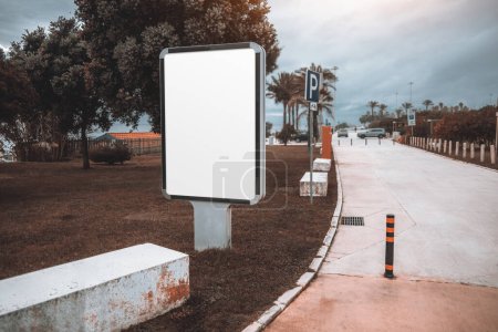 Téléchargez les photos : A blank billboard mockup template on the ground soil near the pedestrian walk, in Estoril; an empty street advertising billboard template with a parking lot nearby; a white advert banner mock-up in urban settings - en image libre de droit