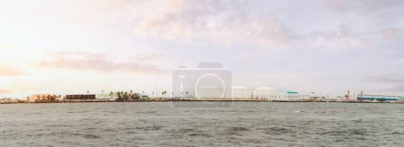 Photo for A panoramic shot of a beautiful island shoreline view, a dock with its airport facilities located in the Maldives, with a dreamy-cloudy lilac shade sunset from the tranquil seawater point of view - Royalty Free Image