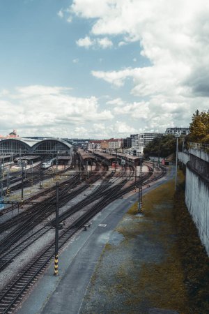 Photo for A vertical shot of a contemporary railroad terminal depot station with plenty of railway junctions and branches, outdoor and indoor platforms, trains, and locomotives on a cloudy day, Prague - Royalty Free Image