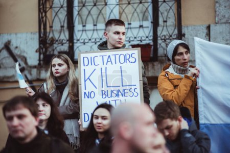 Téléchargez les photos : Lisbon, Portugal - February 24, 2023: Young protestors united on the one-year anniversary of the Ukrainian war; a young man holds a cardboard sign bearing a powerful anti-war message - en image libre de droit