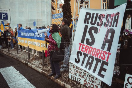 Téléchargez les photos : Lisbonne, Portugal - 24 février 2023 : Au milieu d'un groupe de manifestants tenant des drapeaux et des planches, une femme crie à travers un mégaphone lors d'une manifestation marquant le premier anniversaire du conflit en Ukraine - en image libre de droit