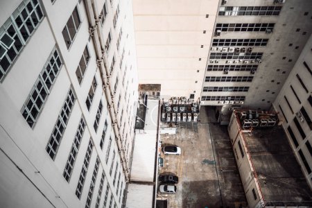 Foto de Top-down capture from a building overlooking an outdoor space common to the surrounding high-rise buildings, with private parking with some cars parked and air conditioning for the dwellings - Imagen libre de derechos