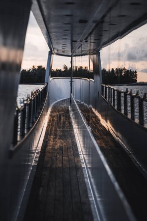 Foto de Un disparo vertical desde la cubierta de un barco es una captura única de una puesta de sol reflejada por la pared del barco, el paisaje marino sereno en el fondo en poca profundidad de campo es hermoso - Imagen libre de derechos