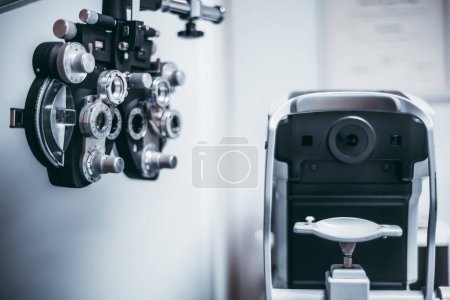 Photo for A black Ophthalmic Phoropter Machine stands out with its sleek and futuristic design; looking right, an equipment for measuring intraocular pressure adds a touch of clinical precision to the setting - Royalty Free Image