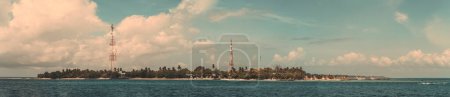 Téléchargez les photos : Une vue panoramique à couper le souffle sur le littoral d'une magnifique île des Maldives, avec une végétation luxuriante et deux tours répétitrices de signaux qui se détachent du paysage naturel - en image libre de droit