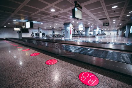 Foto de Una zona de recogida de equipaje clara en el aeropuerto de Lisboa, discreto. En el suelo, círculos con dibujos de dos pies, para que las personas mantengan una distancia segura como medida de salud pública durante la pandemia de covid-19 - Imagen libre de derechos