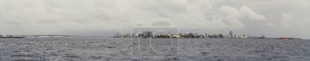 Téléchargez les photos : Vue panoramique du paysage urbain de Male, le long pont domine le côté droit de l'image, entouré par la mer. Le mélange unique de la vie urbaine et un environnement naturel magnifique aux Maldives. - en image libre de droit