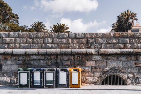 Foto de Estoril; Una pared hecha de puntos ecológicos de arenisca, dispuestos horizontalmente a lo largo del paseo marítimo, para plástico, vidrio, papel y residuos orgánicos, promoviendo la conciencia ambiental - Imagen libre de derechos