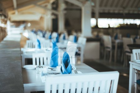 Téléchargez les photos : Maldives ; accent sélectif sur une table avec des serviettes pliées décorativement bleues, de l'argenterie et un sous-plat chic, attirant l'attention sur le décor de la table, soulignant son élégance et son attention aux détails - en image libre de droit