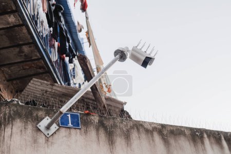 Téléchargez les photos : Lisbonne ; prise de vue en angle bas d'une caméra de surveillance extérieure blanche attachée à un bâtiment très ancien et sale par temps clair dans un quartier humble - en image libre de droit