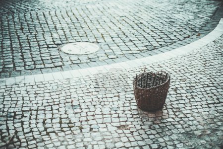 Foto de Las calles de Lisboa cobran vida en este plano de poca profundidad. El enfoque selectivo en una canasta de mimbre marrón resalta detalles intrincados en contraste con el telón de fondo de adoquines y pavimento de piedra volcánica - Imagen libre de derechos