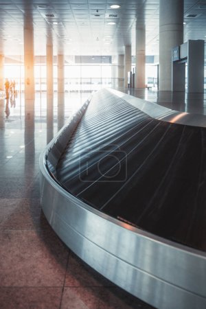 Photo for In Barcelona airport, a vertical shot showcases the empty expanse of a massive luggage conveyor belt, symbolizing the anticipation of travelers and the efficient operations of the airport - Royalty Free Image