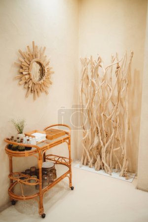 Foto de Foto vertical de una casa de inspiración rústica en Barcelona. Las paredes de color beige, los elementos de madera y el espejo crean calor. Una mesa de centro de ratán con artículos decorativos, y hierbas añaden un toque natural - Imagen libre de derechos