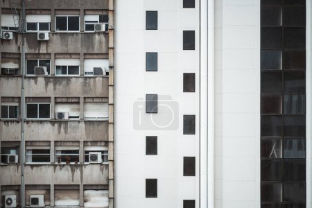 Foto de Fachadas contrastantes, a la izquierda, es un apartamento climatizado con múltiples acondicionadores de aire, mientras que a la derecha, una moderna vivienda blanca con elegantes ventanas rectangulares forma una sorprendente dicotomía visual - Imagen libre de derechos