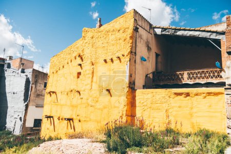 Téléchargez les photos : À Caldes de Montbui, en Espagne, un ancien bâtiment résidentiel altérée est orné d'une peinture jaune vif et vif avec une texture drôle. La couleur respire un sentiment de vivacité à l'environnement - en image libre de droit