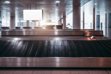 Photo for Lisbon; Luggage claim area; A conveyor belt featuring a white blank mockup in the back. The grey-toned surroundings are impeccably illuminated with bright white lights - Royalty Free Image