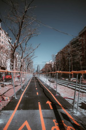 Foto de Barcelona urbana: un carril bici emerge en medio de la construcción de carreteras, vigilado por la seguridad del ciclista. Vibrantes señales de tráfico naranja adornan el camino, simbolizando una ciudad que abarca el transporte sostenible - Imagen libre de derechos