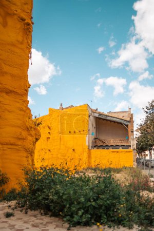 Téléchargez les photos : Un plan vertical de bâtiments inachevés ou partiellement démolis à Caldes de Montbui, en Espagne, est partiellement recouvert d'une peinture jaune éclatante, éventuellement appliquée comme mesure de protection contre la dégradation - en image libre de droit