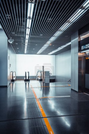 Foto de Una toma vertical de gran angular de una entrada de metro contemporánea con ascensor, escaleras mecánicas y escaleras; un moderno pasillo interior del aeropuerto con un techo de reducción de ruido rayado, marcas amarillas en el suelo - Imagen libre de derechos