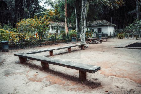 Photo for Rustic scene of a sturdy concrete bench set in a serene park, surrounded by lush greenery and traditional garden elements. This inviting space is perfect for relaxation amidst nature's tranquility - Royalty Free Image