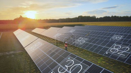 Photo for Engineer performs maintenance work on solar panels in green meadow with digital device. Animation, state of charge energy generation, green, climate-neutral energy source - Royalty Free Image