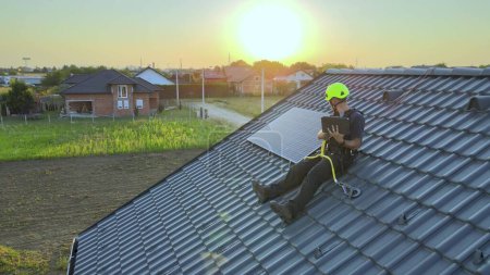 Téléchargez les photos : Ingénieur solaire surveillant l'efficacité et la production d'énergie des panneaux sur le toit - en image libre de droit