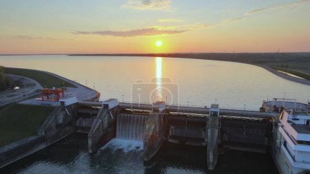 Hydroelectric dam power plant station production of energy supply for city life. Aerial view during colorful sunset big lake natural unpolluted landscape