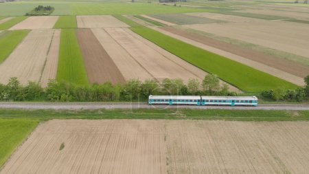 Tren rápido cruza el campo agrícola en un ferrocarril aislado llevando a los trabajadores a su trabajo