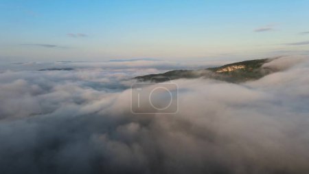 Drone volando sobre la manta blanca de densas nubes que cubren las montañas. Antena