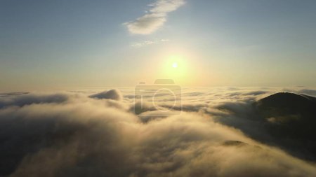 Drone flight over the clouds during sunset. Aerial view during golden hour natural mountain landscape