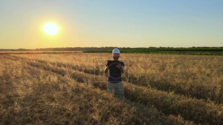 Photo for Male agriculture engineer collecting digital data with tablet on agricultural golden wheat field during sunset. Futuristic technology of ecology - Royalty Free Image